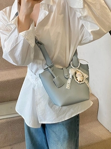 Light blue lychee texture bucket bag with pearl rabbit charm worn by model on stairs