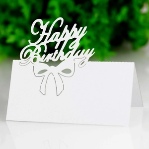 Detail of white laser-cut Happy Birthday table card with hollow bow decoration for parties