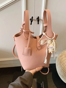 Pink lychee leather bucket bag with pearl lace charms and adjustable shoulder strap