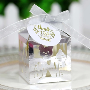 Détail de boîte cadeau argentée ajourée avec motifs ours et biberon pour bébés
