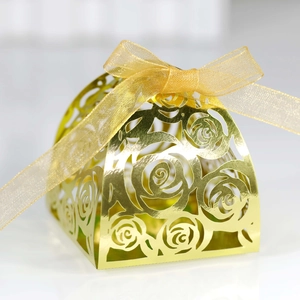 Detail showing laser-cut rose patterns on a gold candy box with a ribbon bow
