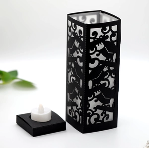 Detail of black laser-cut hollow candle holder with LED electronic light and floral patterns