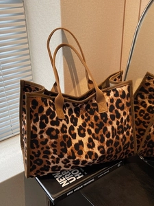 Large capacity leopard print tote bag with brown straps in a minimalist interior setting