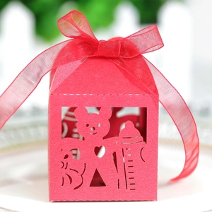 Macro detail of red laser-cut baby shower candy box with bear and bottle hollow patterns