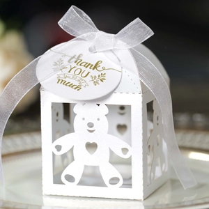 Detail van witte lasergesneden beertje snoepdoos met bedanklabel en wit satijnen lint