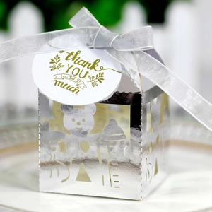 Détail de la boîte cadeau argentée ajourée avec motifs bébé et étiquette merci