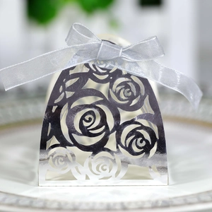 Macro detail of laser-cut rose hollow wedding favor box with a silver silk ribbon