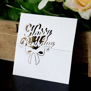 Macro detail of laser-cut pearl paper card with Happy Birthday text and bow design