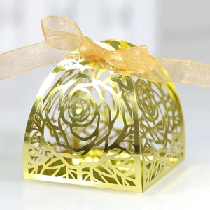 Macro detail of laser-cut rose pattern on gold metallic candy gift box with ribbon