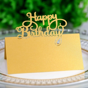 Macro detail of laser-cut gold Happy Birthday table card on a white ceramic plate