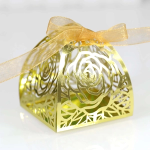 Detailed laser-cut rose patterns on a gold candy gift box with a silk ribbon bow