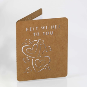 Detail view of laser-cut heart pattern on brown kraft paper greeting card with best wishes