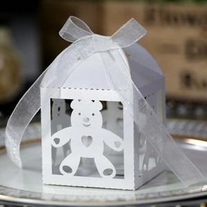 Detail of white laser-cut teddy bear gift box with silk ribbon on a porcelain plate