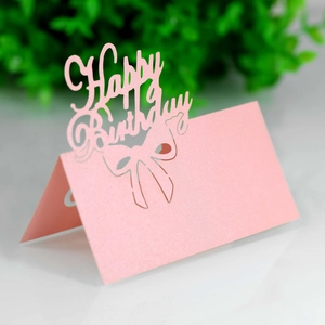 Macro shot of pink pearlescent Happy Birthday seat card with laser-cut bow detail