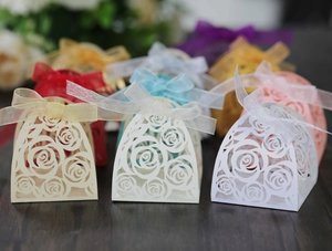 Close-up of laser-cut rose hollow favor boxes with elegant ribbons for wedding candy