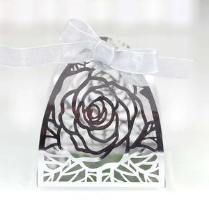 Detailed laser-cut silver candy box with rose pattern and elegant white silk ribbon bow