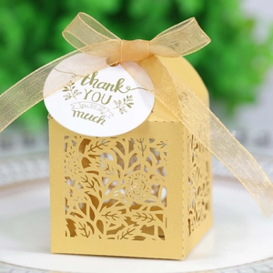 Macro shot of laser-cut rose hollow favor box with gold ribbon and thank you tag