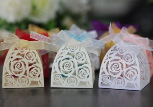 Laser-cut wedding favor boxes with rose patterns and silk ribbons in multiple colors