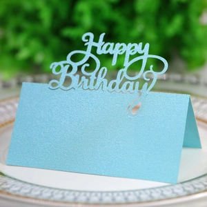Close-up of light blue pearlescent Happy Birthday laser cut place card on a white plate