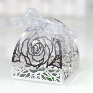 Detail of silver laser-cut candy box with rose pattern and elegant silk ribbon bow
