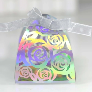 Close-up of holographic laser-cut candy box featuring hollow rose patterns and ribbon