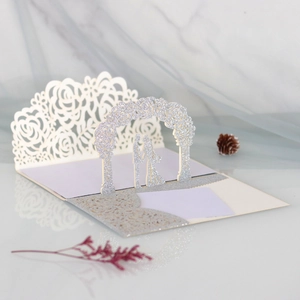 Detailed macro view of laser-cut ivory rose pattern and pop-up silver glitter wedding card