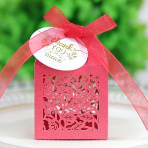 Detail of red laser-cut candy box with floral patterns, ribbon, and thank you tag