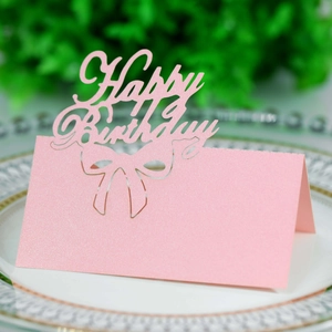 Close-up of pink glitter Happy Birthday place cards with hollow design on a white plate