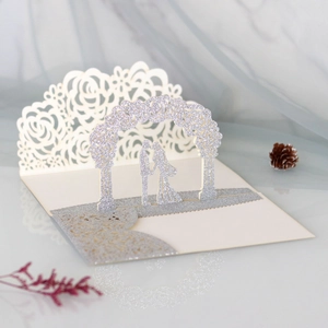 Macro detail of laser-cut 3D wedding card with silver glitter arch and couple silhouette
