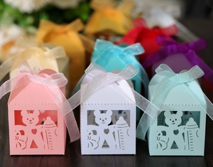 Close-up of laser-cut paper baby shower favor boxes with bear motifs and organza ribbons