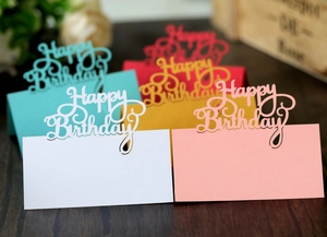 Detail of laser-cut Happy Birthday table cards in multiple colors with pearlescent finish