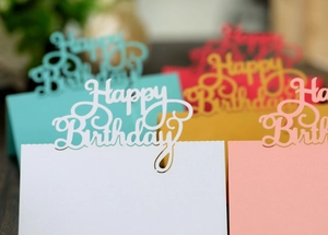 Macro shot of colorful hollow Happy Birthday place cards with intricate laser cut design