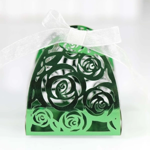 Detail of emerald green laser-cut gift box featuring rose patterns and white ribbon