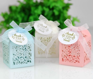 Detail view of laser-cut rose gift boxes with ribbon and thank you tags in soft colors