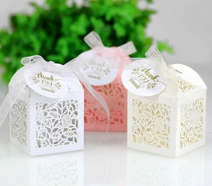 Close-up of laser-cut floral paper gift boxes with silk ribbons and golden thank you tags