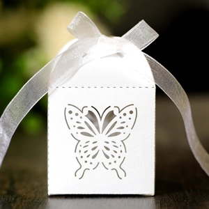 Close-up of laser-cut butterfly pattern on white candy box with elegant ribbon tie