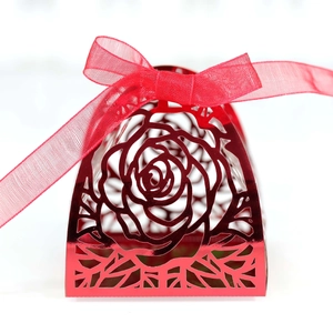 Detail of laser-cut rose patterns on a metallic red gift box with a sheer organza ribbon