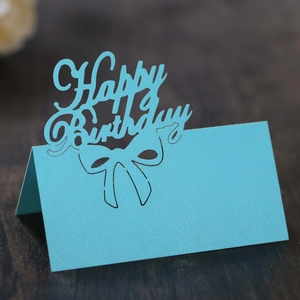 Blue laser cut hollow Happy Birthday table tent card with bow pattern on wood background