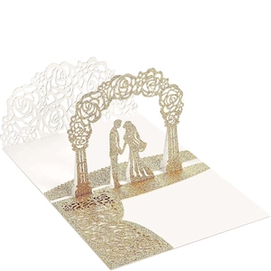 Macro detail of laser cut 3D pop-up wedding card with gold glitter rose arch and couple