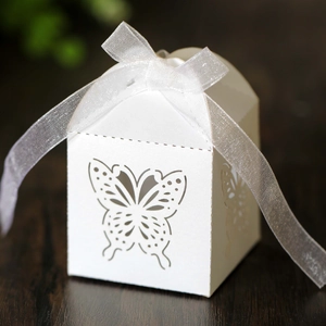 Detail of laser-cut butterfly gift box with white organza ribbon on wooden surface