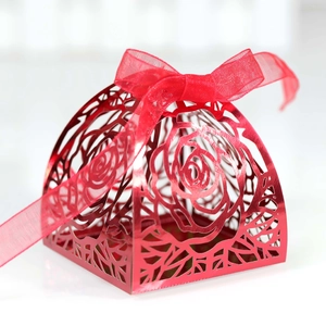 Macro shot of red laser-cut rose hollow candy box with matching organza ribbon bow