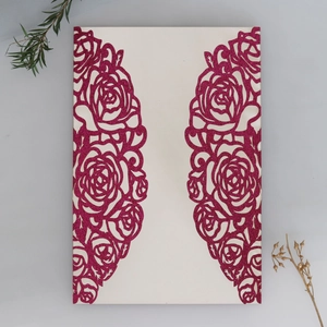 Detail van lasergesneden rozenpatronen met roze glitter op een witte huwelijksuitnodiging