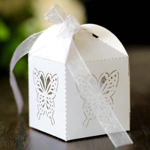 Macro detail of laser-cut butterfly patterns on white paper wedding favor candy box
