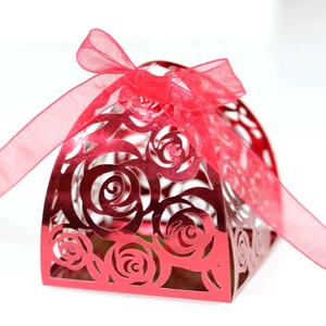 Close-up of red laser-cut rose hollow candy box with metallic finish and ribbon