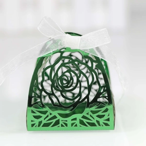 Macro detail of laser-cut green rose pattern on wedding candy box with ribbon