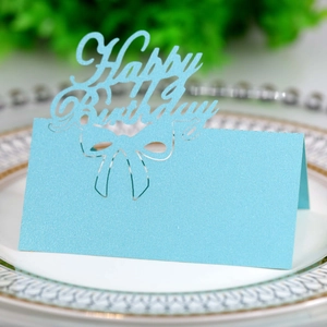 Macro shot of light blue laser-cut Happy Birthday place card with glitter texture