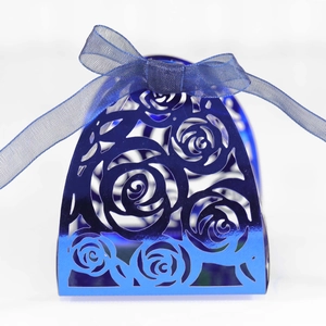 Close-up of laser-cut rose hollow patterns on metallic blue candy gift box with ribbon