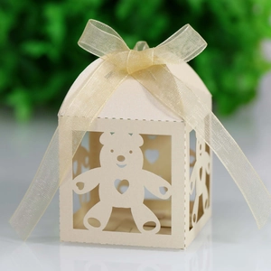 Detail of laser-cut bear and heart patterns on cream paper gift box with organza bow