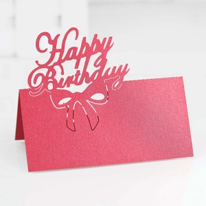 Macro detail of red glitter Happy Birthday laser-cut table card with hollow bow design