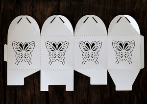 Flat lay of laser-cut butterfly gift box template on a dark wooden background